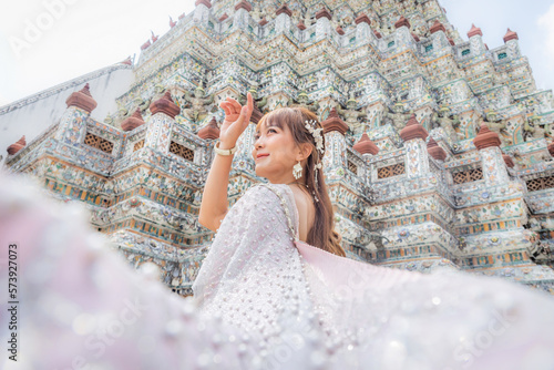 Close up of a young woman wearing traditional Thai dress with accessories standing at Wat Arun, a popular place for tourists around the world. Bangkok Thailand photo