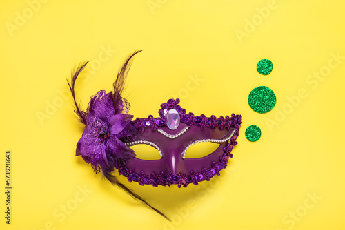Fototapeta Naklejka Na Ścianę i Meble -  Mardi gras lettering. Congratulation card with violet mask on yellow background Top view 2023 Mardi Gras Parade Schedule Mockup Copy space