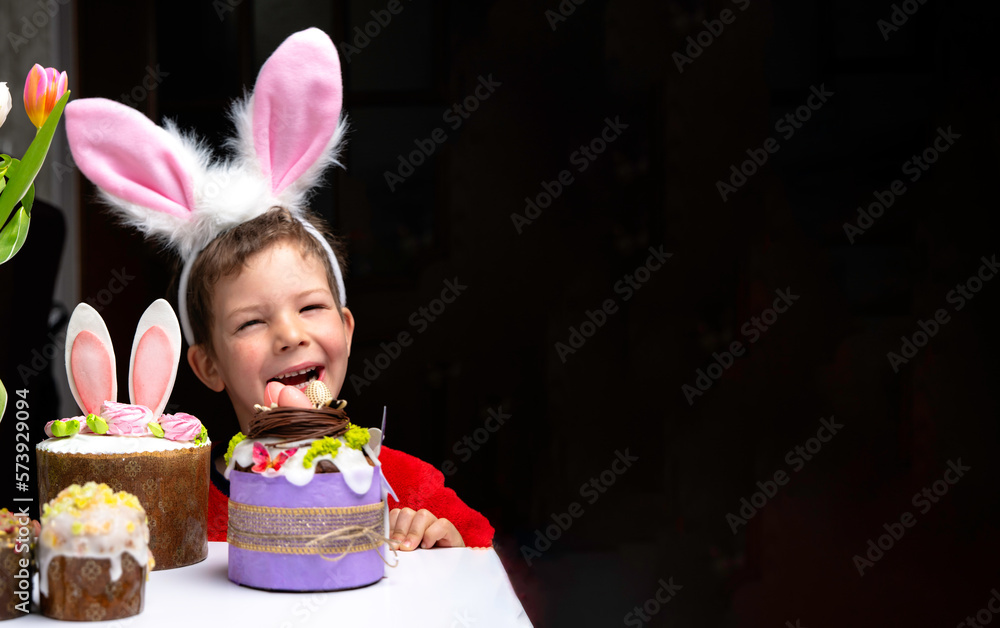 Cute little boy with bunny ears looking at tasty easter sweet cake
