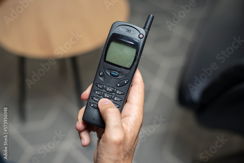 Black retro mobile phone from mid 1990s pressing buttons