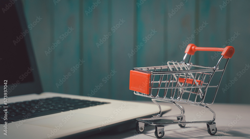 Shopping online. Trolley in front laptop keyboard. Business retail shop store marketing online. Shipping service technology, order check out website, home delivery package, client buying on e-commerce