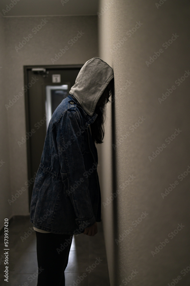 Silhouette of a depressed woman on the walkway of an apartment building. Sad woman, crying, drama, lonely and unhappy concept.