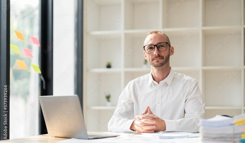 Businessman using laptop computer in office. Happy middle aged man, entrepreneur, small business owner working online.