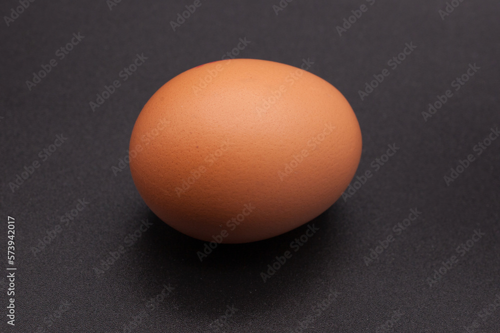 One chicken egg against a black background One chicken egg against a black background