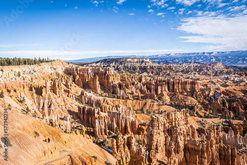 Bryce Canyon accented in freshly fallen snow and distant mountains and brilliantly colored orange cliffs.