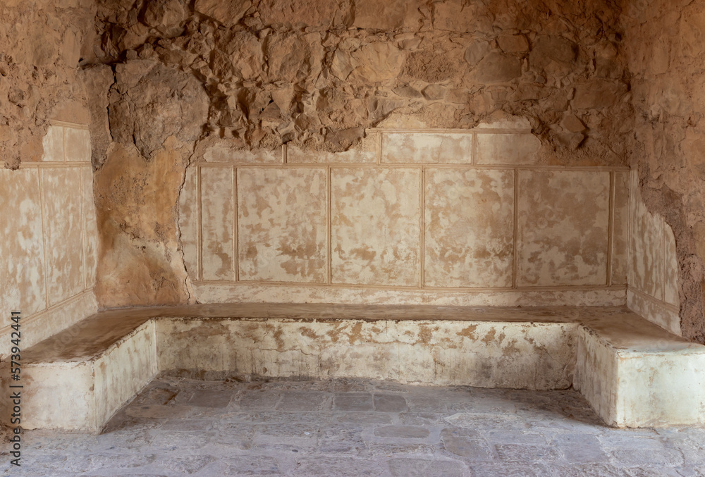 Fototapeta premium The remains of internal buildings in the rays of the rising sun in the ruins of the fortress of Masada - is a fortress built by Herod the Great on a cliff-top off the coast of the Dead Sea, Israel