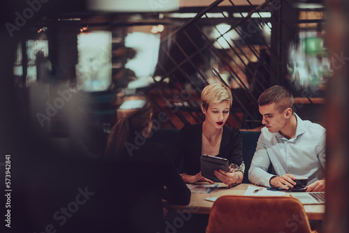 Photo through the glass of a group of business people sitting in a cafe and discussing business plans and ideas for new online commercial services