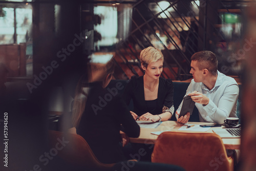 Photo through the glass of a group of business people sitting in a cafe and discussing business plans and ideas for new online commercial services