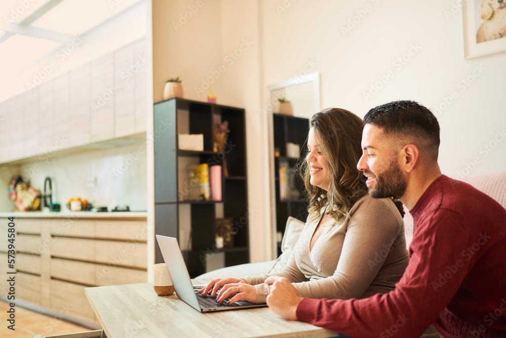 Happy couple using laptop in kitchen
