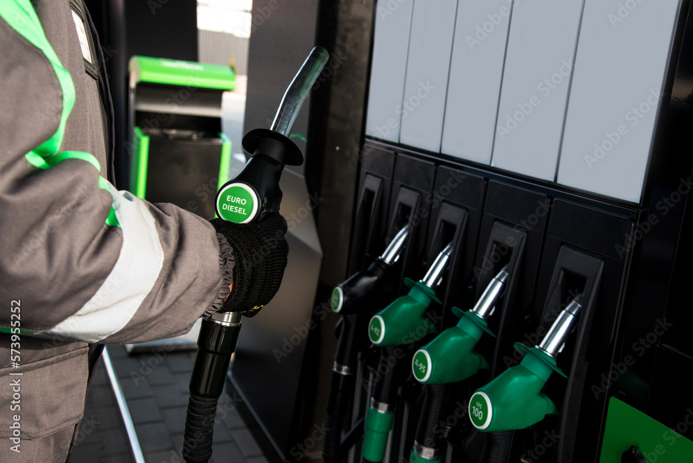 A gas station attendant at a gas station holds a gun with the inscription Eurodiesel