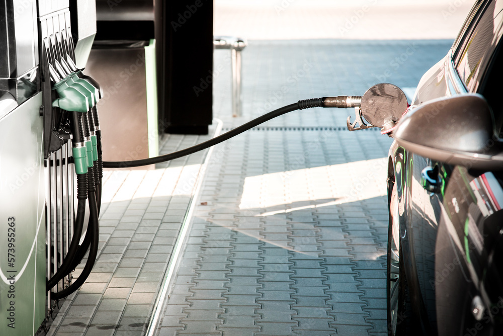 Image of a car gas station with a gun stuck in the car tank and a fuel hose