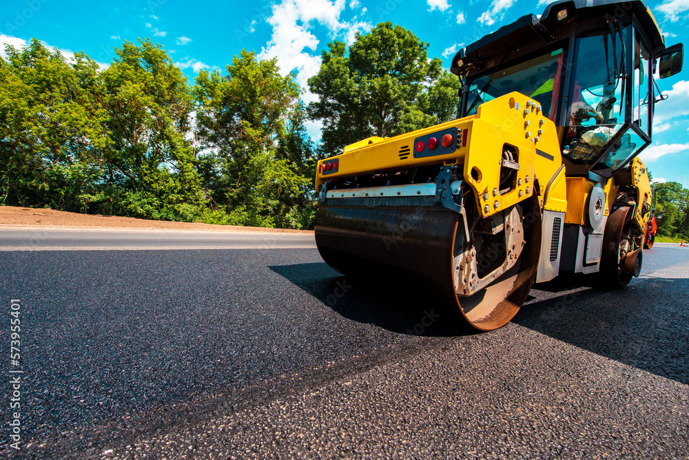 industrial landscape with rollers that rolls a new asphalt in the roadway. Repair, complicated transport movement.