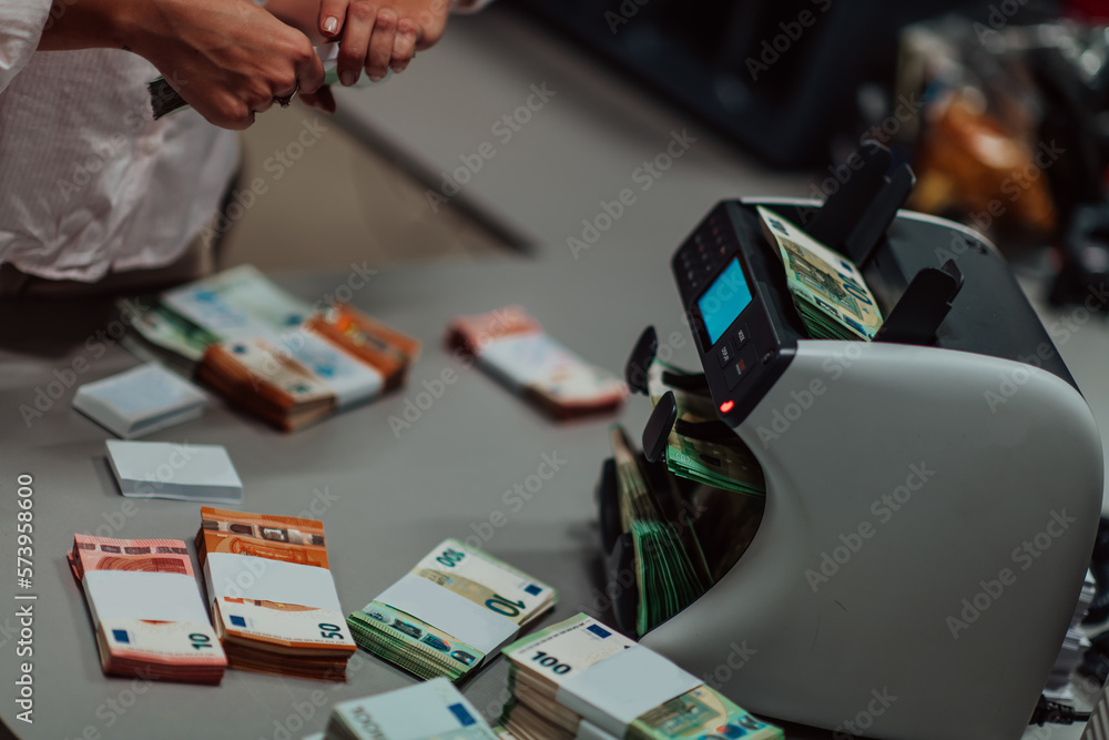 Bank employees using money counting machine while sorting and counting paper banknotes inside bank vault. Large amounts of money in the bank Bank employees using money counting machine while sorting and counting paper banknotes inside bank vault. Large amounts of money in the bank