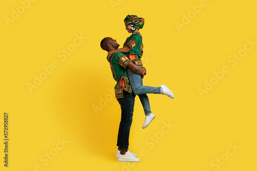 Romantic black couple in african outfit cuddling on yellow