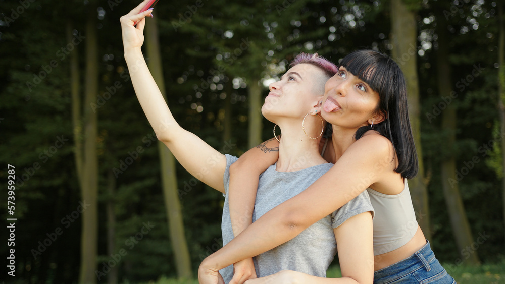 Happy loving homosexual lesbian LGBT couple taking a selfie on the smartphone and kissing Happy loving homosexual lesbian LGBT couple taking a selfie on the smartphone and kissing