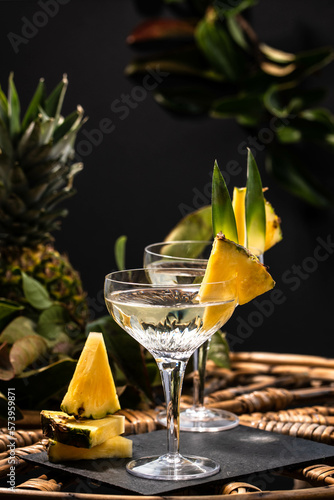 Champagne cocktail with pineapple decoration on a rattan table