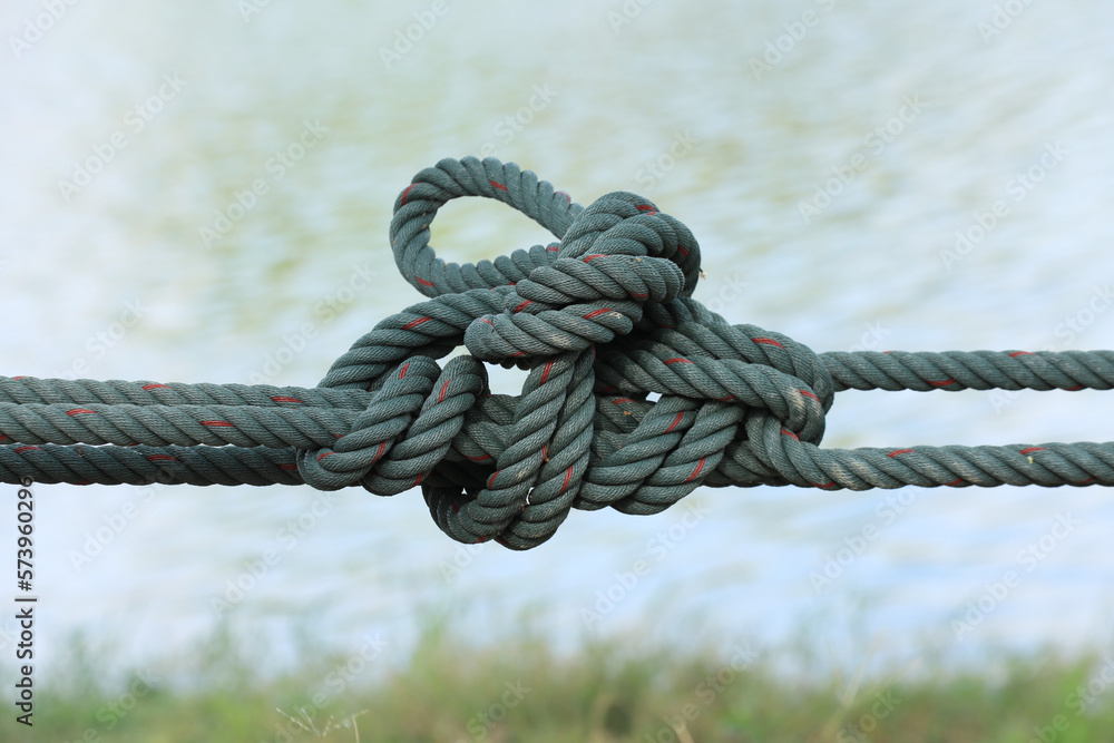 Twisted green cord on blurred water surface background. - obrazy, fototapety, plakaty 