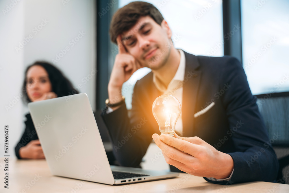 Businessman standing at a workstation with a lightbulb in his hand. Inventive company concept. Businessman standing at a workstation with a lightbulb in his hand. Inventive company concept.