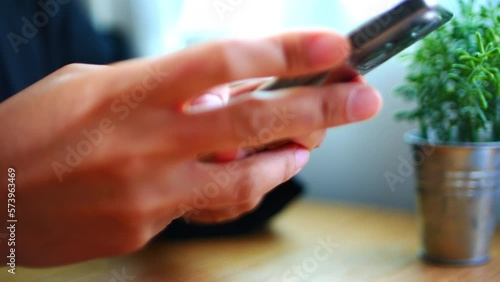 Woman's hand using smartphone at home typing text. Close-up of a young woman's hand