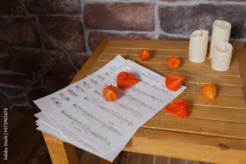 A sheet of music is lying on a wooden table with a brick wall in the background.