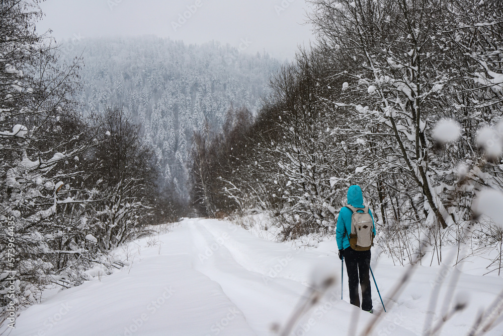Gloomy photo of a hiker girl walking through a dark forest during a snowstorm; hiking in the mountains during a cold winter Gloomy photo of a hiker girl walking through a dark forest during a snowstorm; hiking in the mountains during a cold winter