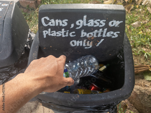 Male hand throwing plastic bottles into the bin for waste plastic bottles
