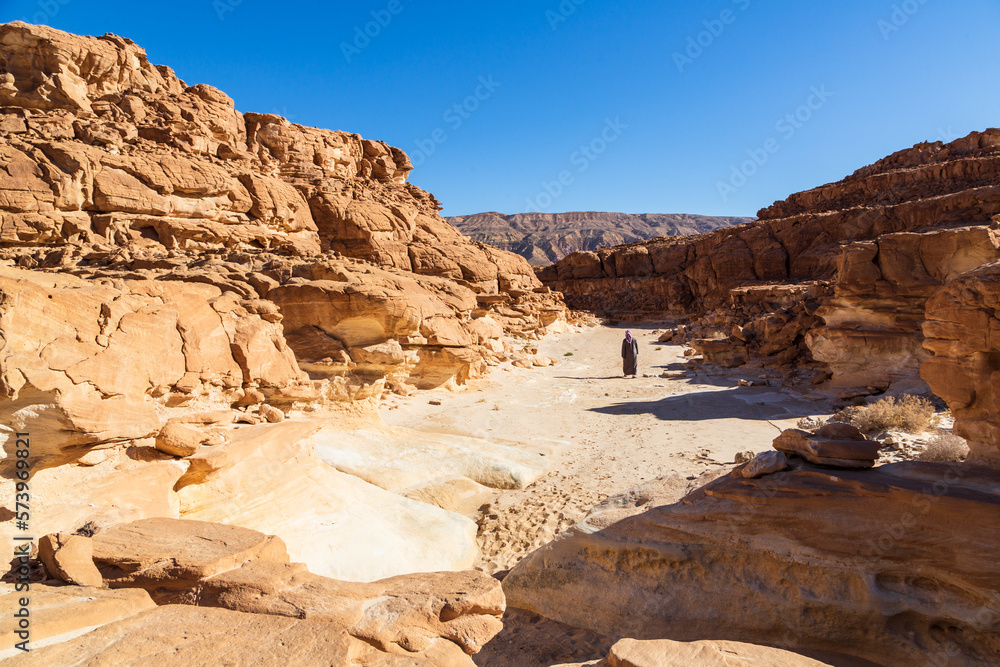 Sinai peninsula, Egypt - 30 January 2022: Bedouin walking in a canyon, bizarre rock formation located in the Sinai mountain range. Outdoor travel background, popular tourist attraction