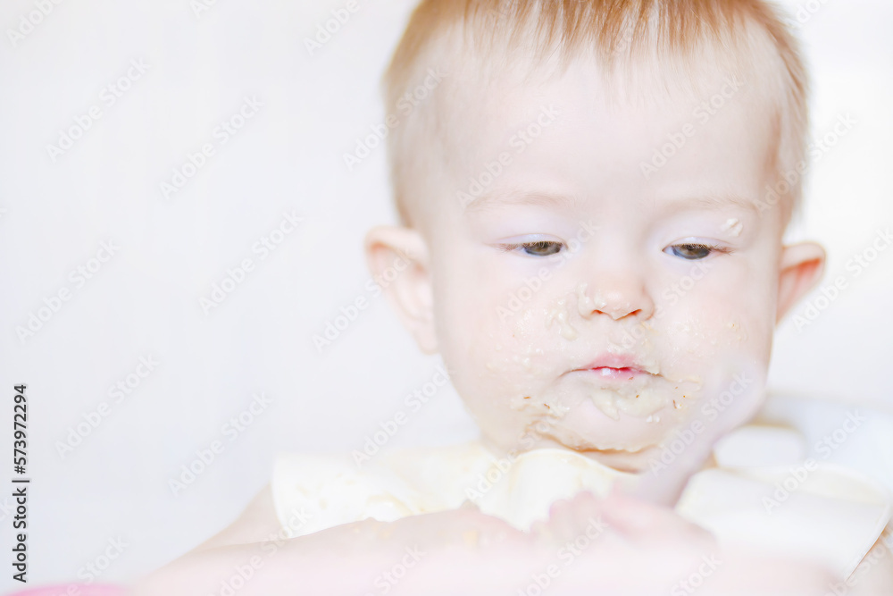 Happy childhood and delicious food. Funny child gets dirty with food. Little cute kid eats with his hands. Grimaces of a cheery baby. Close-up of a child's face Happy childhood and delicious food. Funny child gets dirty with food. Little cute kid eats with his hands. Grimaces of a cheery baby. Close-up of a child's face