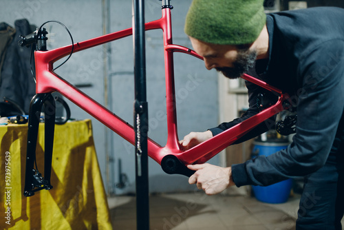 Mechanic repairman assembling with wrench custom bicycle in workshop