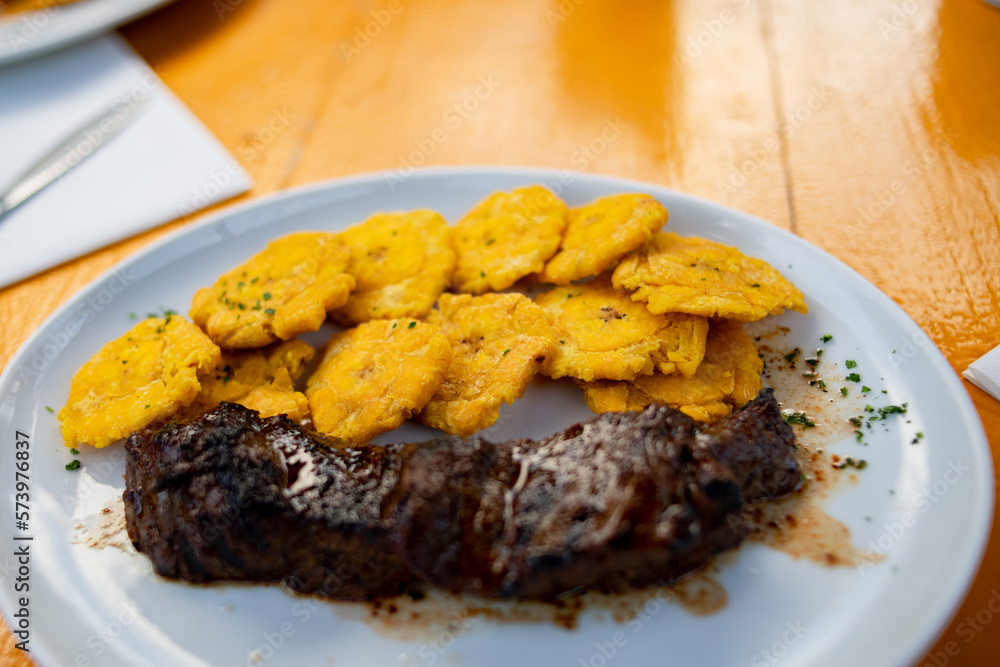 tostones with beef fillet served on white plate. Fried green plantain. Dominican food. Stepped potato.