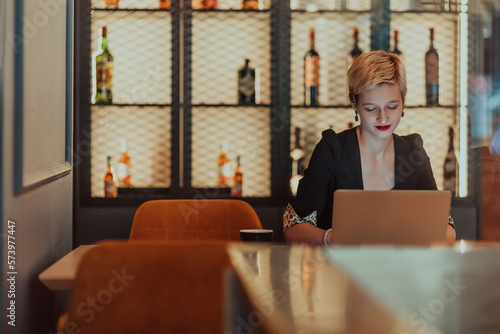 Businesswoman sitting in a cafe while focused on working on a laptop and participating in an online meetings. Selective focus.