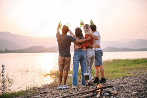 Canvastavla Group of people clinking bottle of beer into the sky while hanging out with friends, camping outdoors lifestyle on summer vacation