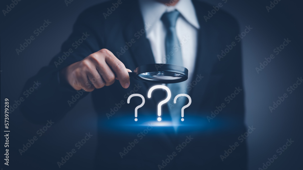 businessman hand holding a magnifying glass with question mark icon , concept of analyzing problem Or find the cause that occurs during the work process - obrazy, fototapety, plakaty 