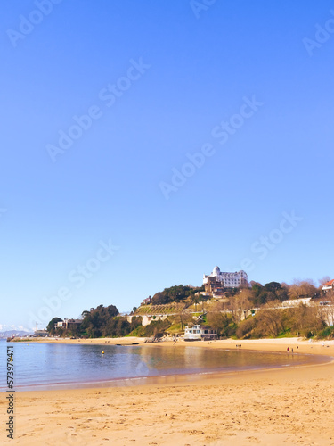 Views of Peligros Beach (Playa de los Peligros) with a famous building and the mountains of the Picos de Europa at the back - Magdalena Peninsula Santander, Cantabria, Spain. Vertical
