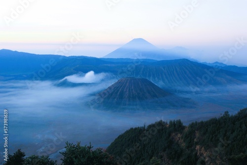 view of the crater of Mount Bromo with Mount Semeru in the background before sunrise with blue sky