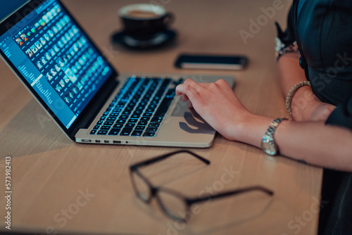 Close up photo of businesswoman sitting in a cafe while focused on working on a laptop and participating in an online meetings. Selective focus. 