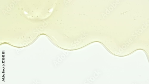Yellow Transparent Cosmetic Gel Fluid With Molecule Bubbles Flowing On The Plain White Surface. Macro Shot. High quality 4k footage