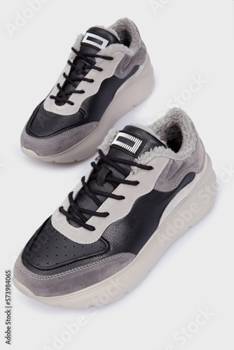Pair of grey fashion leather warm autumn female tennis sneakers. Women's sports training shoes with fur isolated on white background. Template