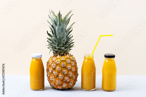 Pineapple and a fresh healthy smoothie in a glass bottles and a straw on a blue background. Healthy, detox and dietary nutrition concept.