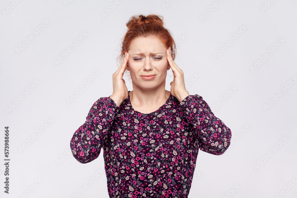 Unhealthy sick redhead woman wearing dress massaging temples, suffering from headache, migraine. Unhealthy sick redhead woman wearing dress massaging temples, suffering from headache, migraine.