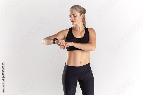 Smiling sporty blonde woman looking at fitness tracker and checking loss calories.