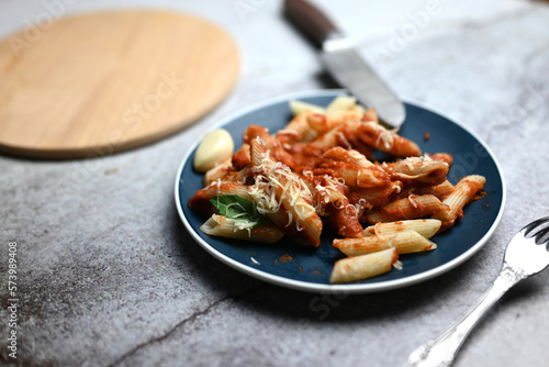 pasta with tomato sauce with grated cheese and food fork and wooden tray