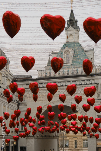 Decorations in Moscow for Valentine's Day. Garlands in the form of red balls in the shape of a heart hang between historical buildings of architecture in daylight.