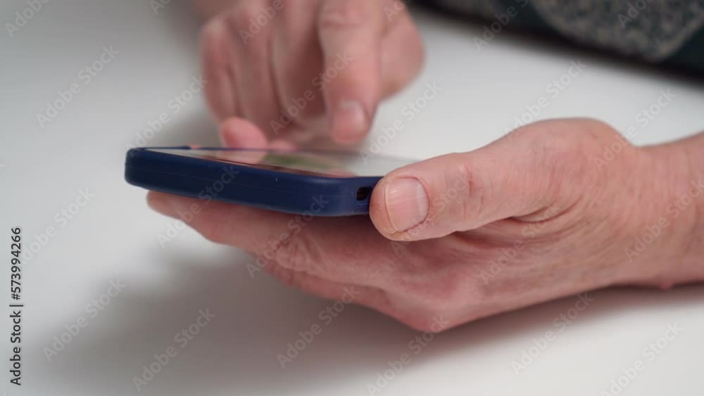 Elderly female hands holding smartphone at table closeup. Aged woman typing message in mobile phone messenger, send message, chatting, texting. Social media communication, modern digital gadget. Elderly female hands holding smartphone at table closeup. Aged woman typing message in mobile phone messenger, send message, chatting, texting. Social media communication, modern digital gadget.