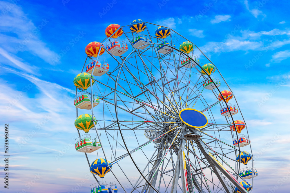 Ferris wheel attraction on blue sky background.