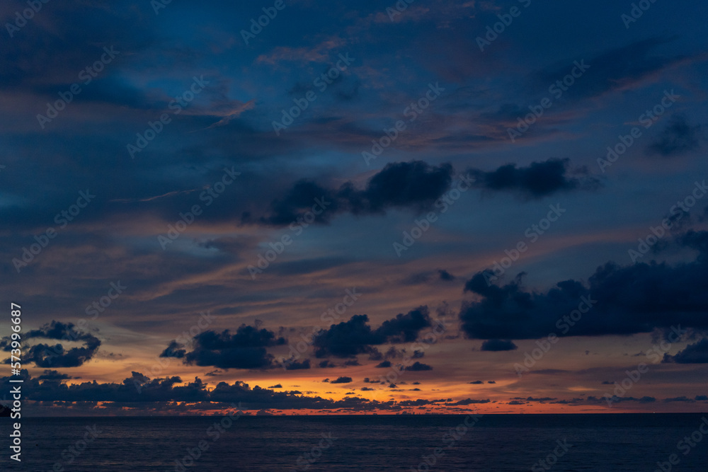 Obraz premium Grainy sea view golden hour sunset shot with dramatic cloud, dark blue sky and deep blue sea