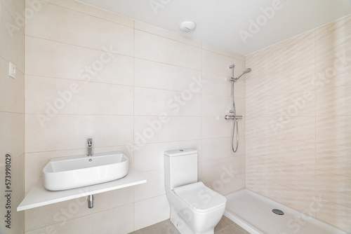 Modern bathroom in white beige tones tile with vanity sink and an open shower in hotel or new apartment. Concept of stylish bathroom interiors with natural light