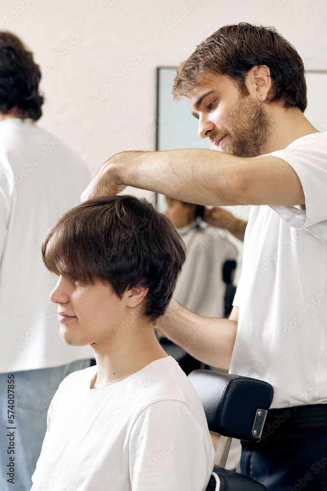 Barber talking to caucasian man while sitting in chair Barber talking to caucasian man while sitting in chair