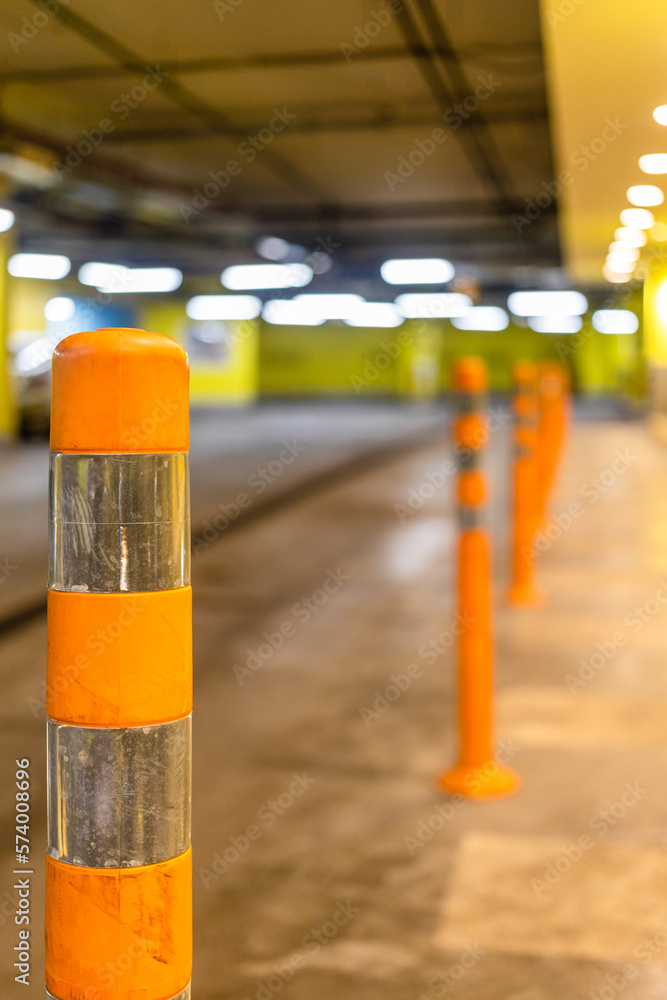 orange reflective security bollard close up in underground parking (focus on the first post on foreground)