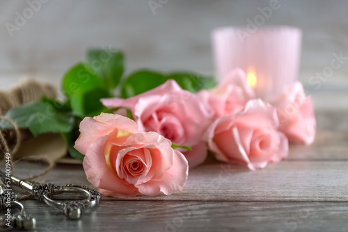 Pink roses  scissors and a candlestick on a wooden table. Postcard. Photo